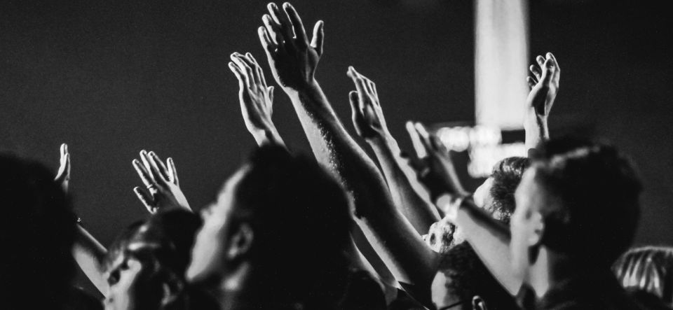 black and white photo of people worshiping with hands raised to God
