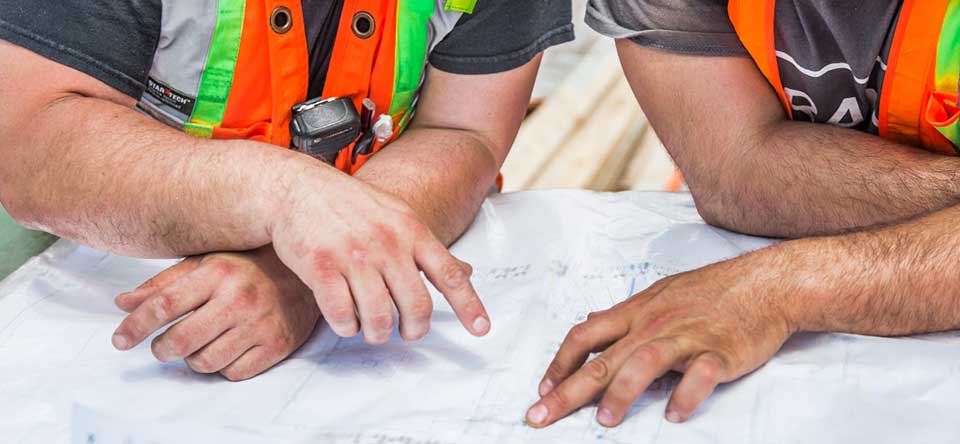 two construction workers pointing to plans