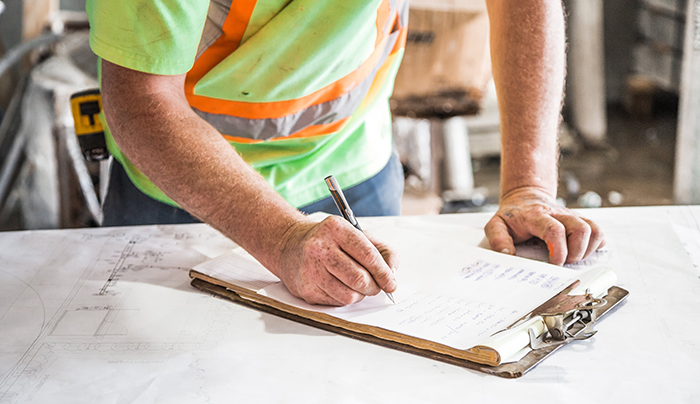 construction worker writing on clipboard