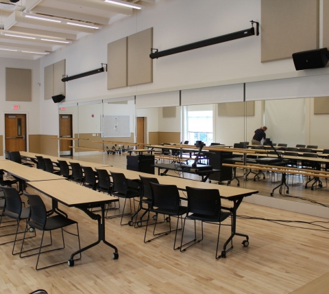 classroom with two long rows of tables and chairs and mirror on front wall