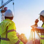 three construction workers looking at crane on jobsite