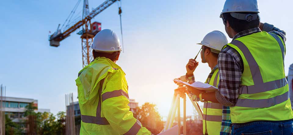 three construction workers looking at crane on jobsite