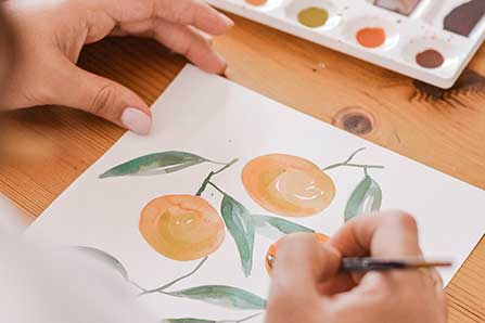 woman painting watercolor oranges