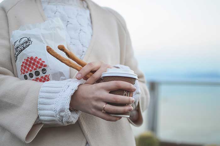 woman tan blazer holding coffee bread sticks