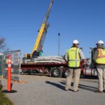 two men on construction site behind crane