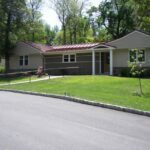 Exterior view of renovated Rosemont senior cottage featuring new siding, stone veneer, and vibrant metal roof, completed by Horst Construction