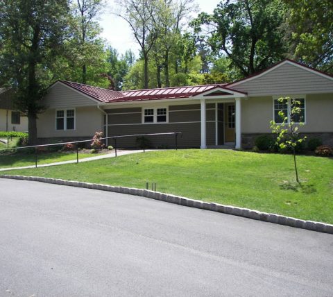 Exterior view of renovated Rosemont senior cottage featuring new siding, stone veneer, and vibrant metal roof, completed by Horst Construction