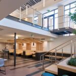 A dining area with booths in a sunny open lobby area